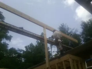 Carpenter setting a ridge beam over a new addition frame — Ice Dam Removal by Roofing Brothers in Max
