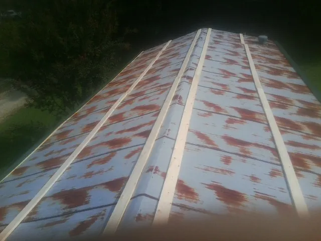 Rusted metal roof panels with new wood purlins before replacement — Storm Damage Roof Repair in Max by Roofing Brothers