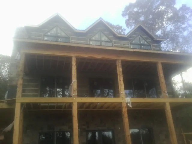 Dormers and porch framing on a large log home under construction — Roof Coating work by our crew in Max