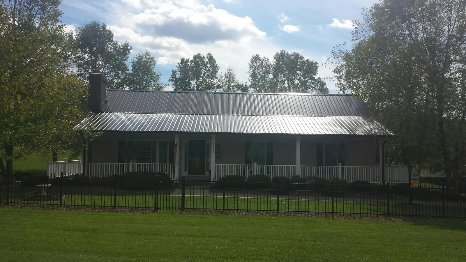 Gray metal roof on a brick ranch with a full width front porch — Gutter Guard Installation work by our crew in Max